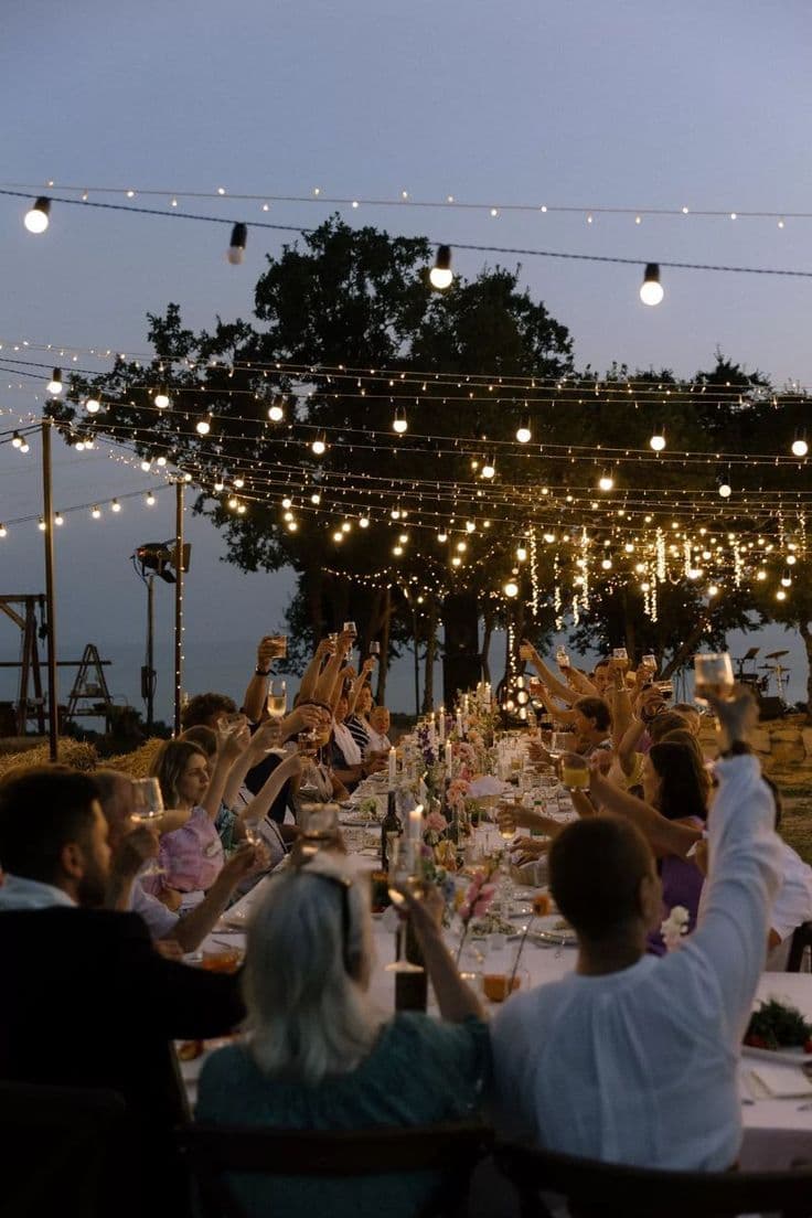 Guests raising glasses under string lights